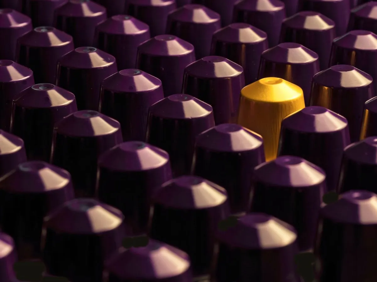 Capsules de café alignées, une jaune se démarque parmi les violettes, choix d'une dosette compatible