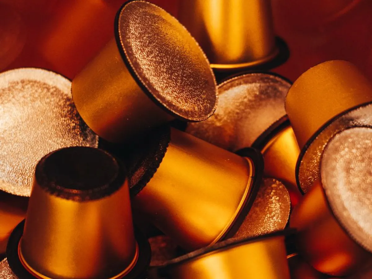 Capsules de café dorées en vrac dans une boîte, comparatif du meilleur café en dosette