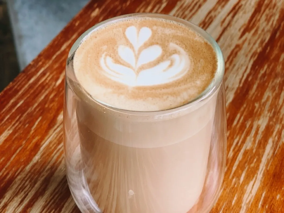 Chai latte crémeux dans un verre, mousse de lait et cœur de latte art sur table en bois