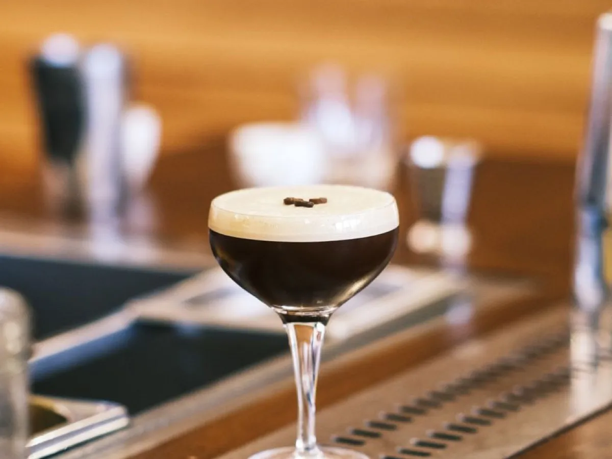 Espresso martini mousseux dans un verre coupe posé sur un bar en bois