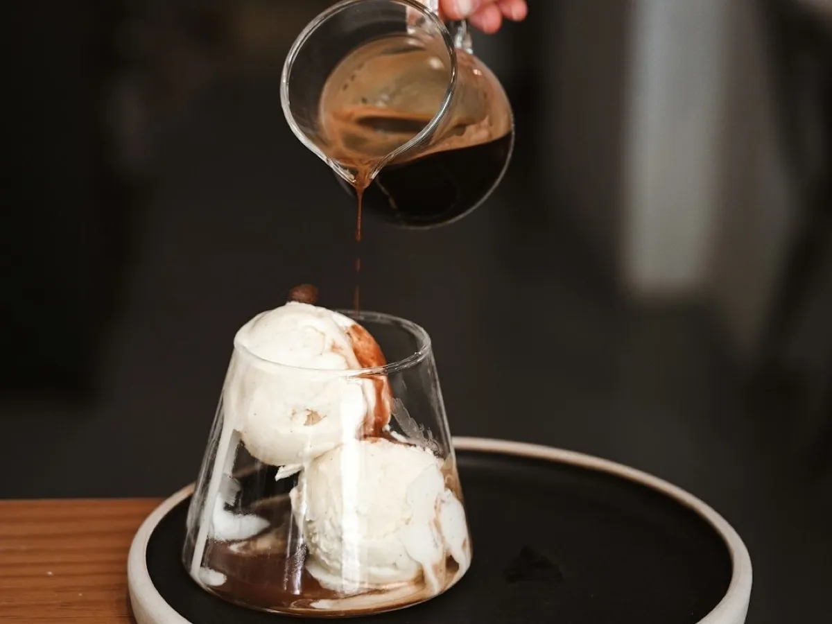 Espresso versé sur des boules de glace vanille dans un verre pour préparer un affogato