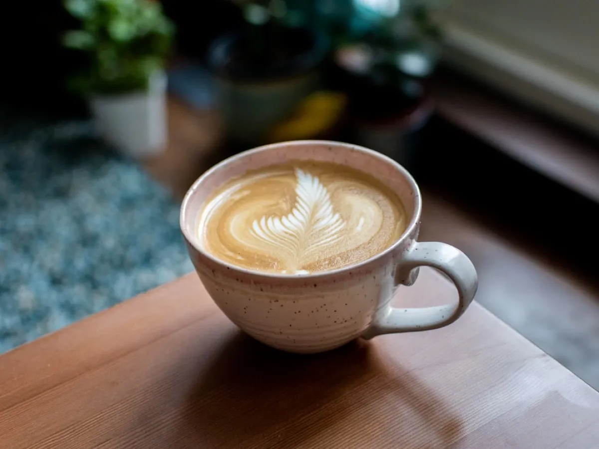 Flat white à la rosetta servi dans une tasse en grès, micro-mousse lisse et brillante