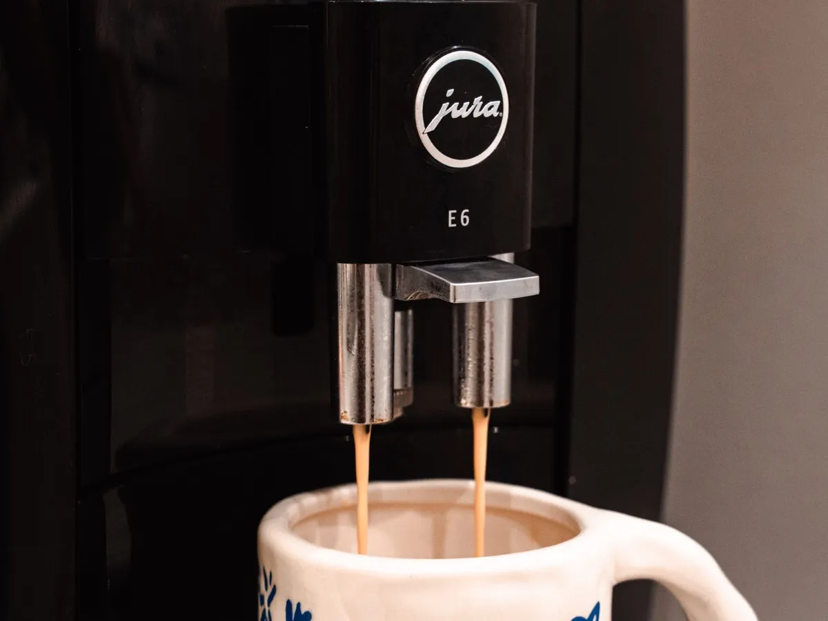 Machine à café Jura E6 versant un expresso dans une tasse artisanale bleue et blanche