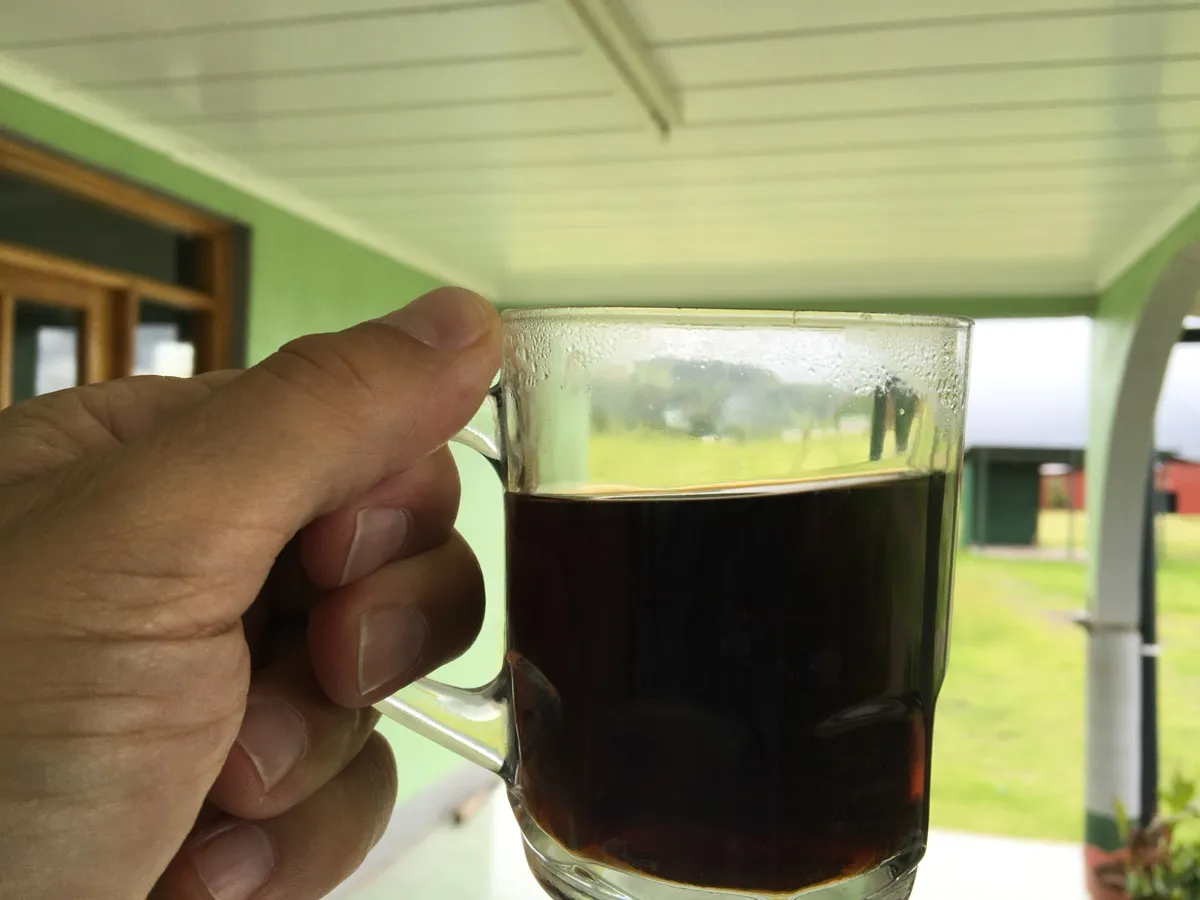 Main tenant une tasse en verre de café noir, combien de café par jour