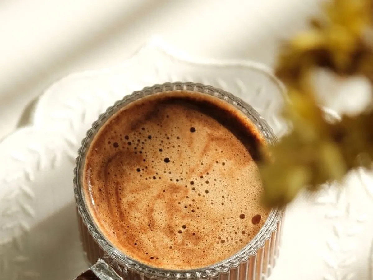 Tasse en verre remplie d'un café crémeux dans la lumière du matin