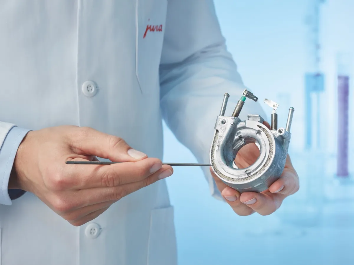 Technicien Jura présentant une pièce interne entartrée d'une machine à café avant détartrage